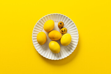 Bright yellow Easter eggs and speckled quail eggs are beautifully arranged on a white plate, creating a cheerful centerpiece perfect for spring festivities and family gatherings
