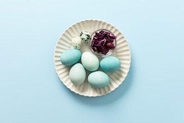 A plate holds several blue-painted Easter eggs and a couple of small patterned eggs, creating a festive atmosphere for the holiday celebration, small bowl of red cabbage, how to dye eggs blue