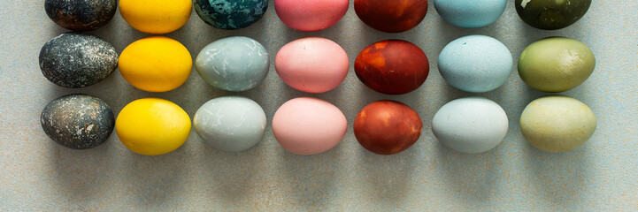 A beautiful array of hand-dyed Easter eggs in various colors, neatly arranged in rows. This colorful display celebrates the spring season and Easter traditions with creativity, banner