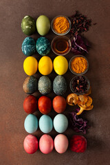A vibrant assortment of Easter eggs rests on a surface, beautifully dyed in various colors. Natural dye ingredients, such as beets, turmeric and hibiscus, red cabbage and onion peel, vinegar
