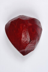 An overhead studio shot captures a single half of a raw, dark red, and roughly carved, peeled beetroot resting on a clean white background