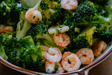 Close up of homemade stir-fried shrimp with broccoli on wooden table