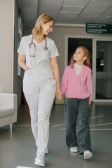Obraz premium Doctor holding girl's hand walking in clinic