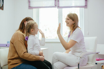 Fototapeta premium Pediatrician high-fiving young girl for successful clinic visit