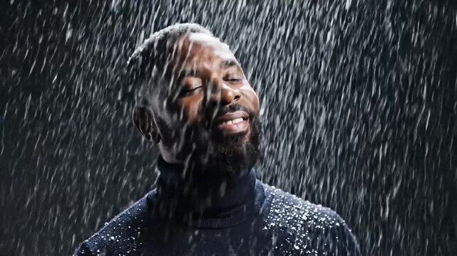 Close Up of African American Man in Dark Blue Turtleneck Under Rain Showers with Dark Background Lit from Below for Dramatic Effect Perfect for Adobe Stock