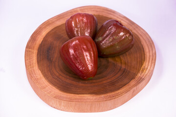 Three very ripe water apples served on a wooden base taken from three quarter angle