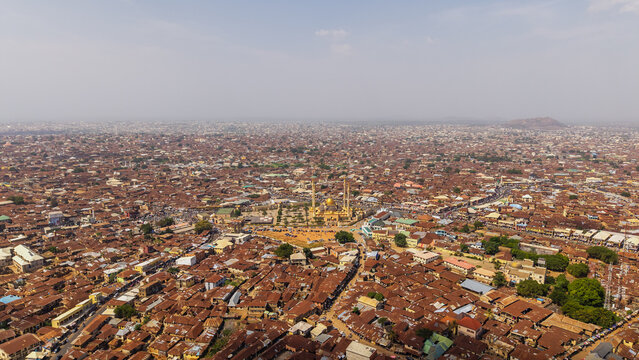 Aerial view of sun-drenched buildings with red roofs sprawling across the urban landscape under a hazy sky, Oko Erin, Kwara, Nigeria.