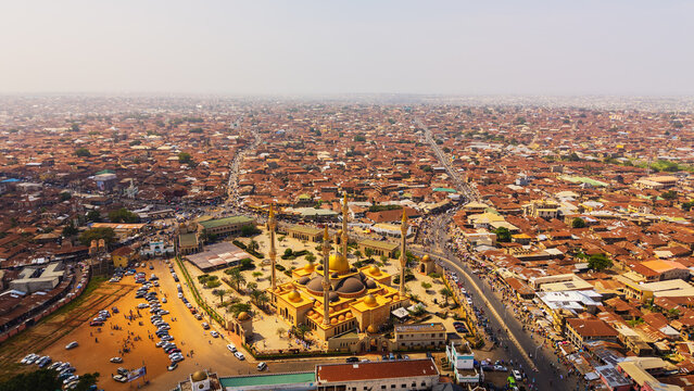 Aerial view of a sprawling cityscape dominated by terracotta rooftops, punctuated by the golden domes and minarets of a grand mosque, Oko Erin, Kwara, Nigeria.