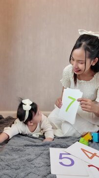 A mother showing number flashcards to her baby in the living room, creating an engaging early learning moment