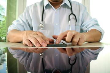 Doctor using smartphone at desk with stethoscope