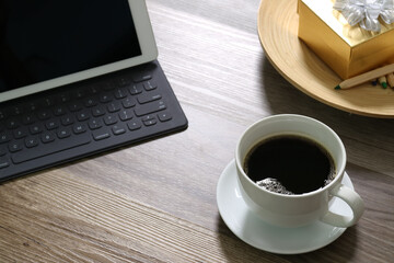 Coffee cup on work desk with tablet and gift box