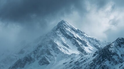 Snow-covered mountain peak rising through mist and dark storm clouds. Concept Snowy mountain peak, Misty atmosphere, Dark storm clouds, Alpine landscape, Dramatic weather
