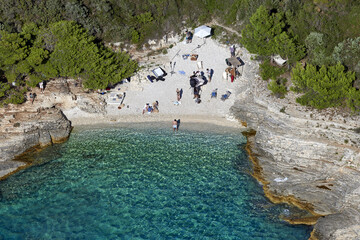 Aerial view of a secluded beach with clear turquoise waters meeting the rocky coastline and lush greenery, Pinizule, Istria County, Croatia.
