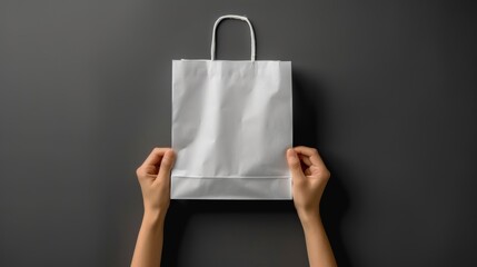 Flat Lay of Person Holding White Paper Shopping Bag on Gray Background, Studio Shot of Minimalist Presentation