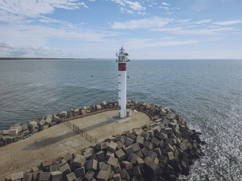 Aerial view of the Faro de El Espignon lighthouse standing tall against the vast ocean, a beacon of hope under a cloudy sky, Huelva, Andalusia, Spain.