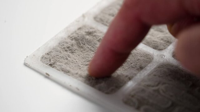 Finger cleaning dust from a dirty air conditioning and ventilation filter close up