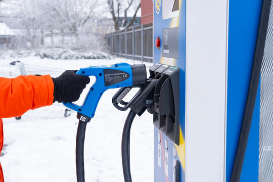 Man in orange coat holding charging plug lidl EV CCS2 quick-charge station, hpc charging connectors, Combined Charging System, alternative energy, technology automotive industry, winter Frankfurt