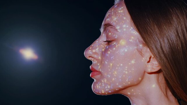 Profile face shows cosmic star projection. Woman closes eye in pose. Galaxy pattern covers cheek and jaw. Light points sparkle on skin and forehead. Portrait highlights model and dreamy cosmic mood.