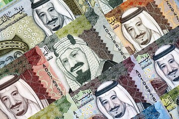 Saudi Arabia riyal money bills banknotes lies in big pile on table close up. Concept of finances...