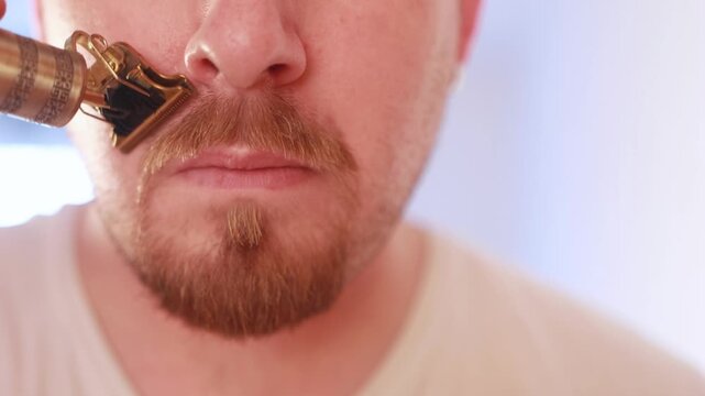 Close view of man trimming goatee with electric shaver