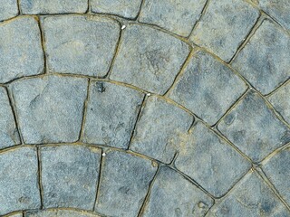 Close-up surface background of textured gray and blue-gray paving stones or cobblestones with a fan-shaped arrangement, perfect for flooring design or backdrop use.
