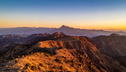 Golden light paints jagged mountain peaks in Arizona at sunset, revealing texture and form