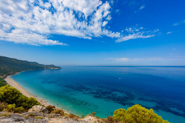 Scenic cliffs near sunny sea shore on a bright clear blue day in Greece. Pefkoulia beach with turquoise water and clear blue sky, Lefkada island, Ionian sea coast
