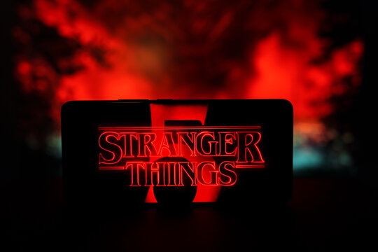 Stranger Things logo on smartphone screen with red smoke background