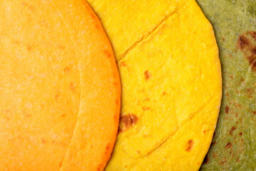 Assorted tortillas of various colors close-up.	Top view. Flat bread made with flour with spinach, turmeric and tomato powder