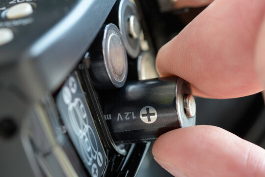 Hand inserts 1.2V battery into electronic device compartment, highlighting correct polarity and concept of portable power for everyday technology