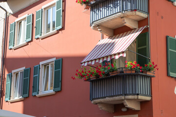 Cozy balcony in an Italian town with warm architecture and charming details. Peaceful Mediterranean atmosphere, flowers, sunlight, and traditional building style