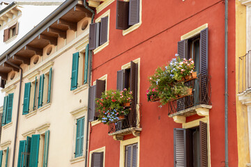 Cozy balcony in Verona, an Italian town with warm architecture and charming details. Peaceful Mediterranean atmosphere, flowers, sunlight, and traditional building style