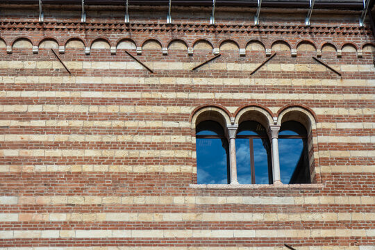 Fototapeta Architectural detail of the Palazzo della Ragione in Verona, Italy, showing its distinctive striped brickwork and elegant triple-arched window in historic medieval style
