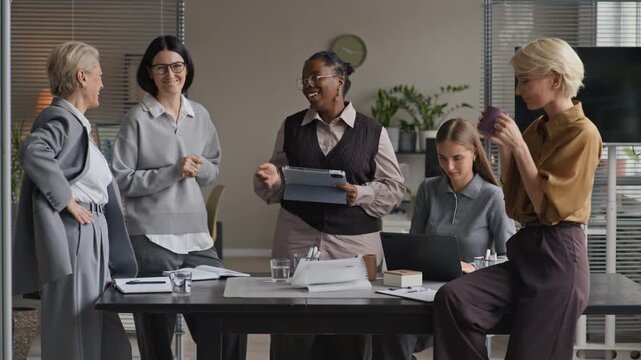 Medium long shot of mature Caucasian female CEO finishing office meeting with female startup team, shaking hands with young Black female employee and appreciating her hard work and motivation