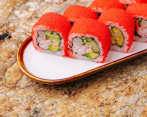 Colorful sushi rolls on a decorative plate with a granite background