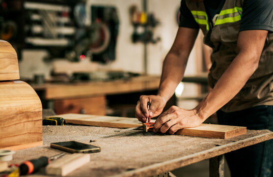 carpenter using vernier calipers to measure a piece in the workshop. Young cabinetmaker measuring a piece on the workshop