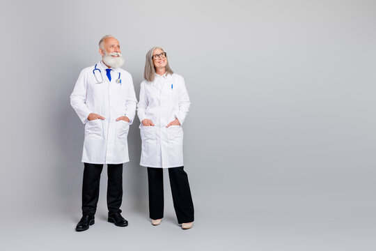 Two experienced doctors stand together in white coats smiling for a medical consultation and healthcare professional hospital clinic imagery