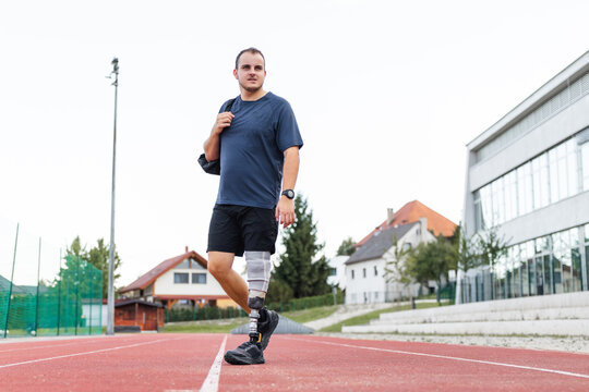 Athlete with a prosthetic leg trains on a running track, focusing on fitness and determination outdoors in daylight.