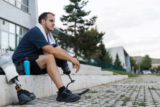 Athlete with leg amputation resting on outdoor steps after workout. Strength, motivation, and healthy living concepts.