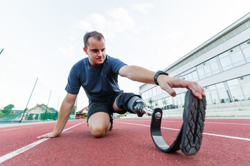 A determined athlete with disability and prosthetic leg practices on an outdoor running track, focusing on his training routine.