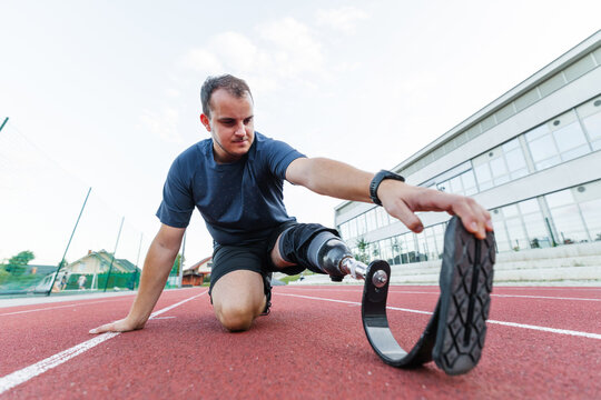 A determined athlete with disability and prosthetic leg practices on an outdoor running track, focusing on his training routine. - Powered by Adobe