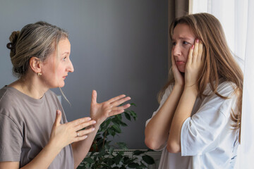Stressed mother yelling at teenage daughter during heated argument at home. Realistic family conflict, generational tension and emotional parenting moment.