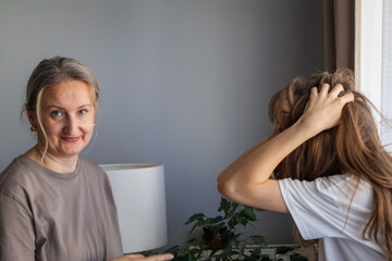 Frustrated teenage girl holding her head in distress after argument with mother. Realistic family tension, emotional burnout and parent–teen conflict