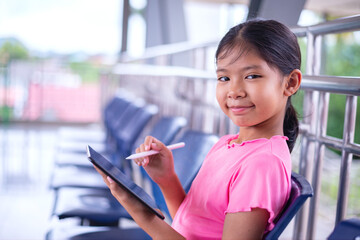 Smiling Young Girl Using Stylus on Digital Tablet
