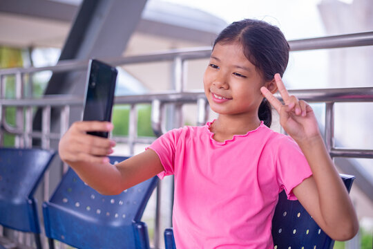 Happy Girl Taking a Selfie with Smartphone While Sitting Outdoors