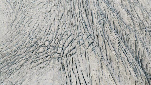 Aerial view of a vast, textured glacier surface, scored with deep crevasses and ridges, displaying a stark and icy landscape, Fjallajokull, Iceland.