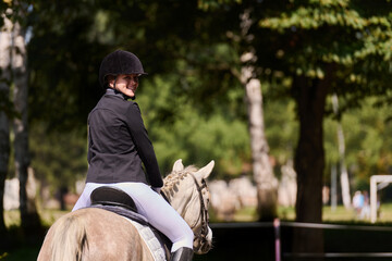 Female equestrian riding horse in outdoor setting, enjoying the sport and connection with the...