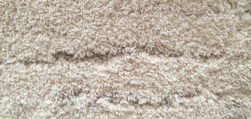 Fluffy carpet texture background. Soft rug for a bathroom or bedroom. Beige or gray fluffy carpet texture. Home interior decor. Terry rug.