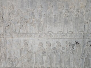 View of ancient stone carvings depicting figures with offerings and a bull, a glimpse into Persepolis' history and art, Marvdasht, Fars Province, Iran.