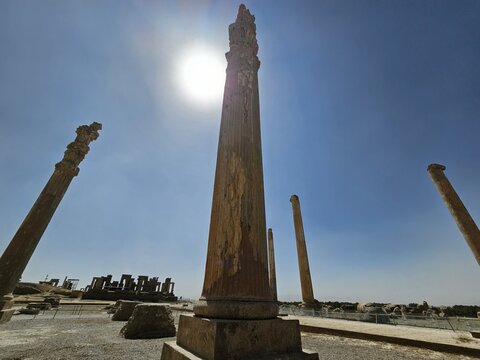 View of ancient columns stand tall against the bright sun and clear blue sky, a testament to history and architectural grandeur, Marvdasht, Fars Province, Iran.